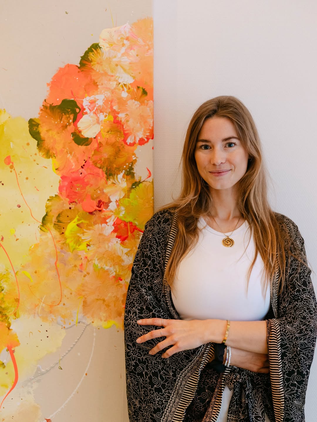 Joana in ihrem Atelier vor einem farbigen Kunstwerk